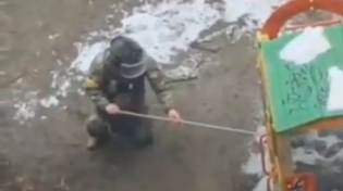 Thumbnail for A Ukrainian soldier in a protective suit carries an IED / Molotov cocktail to the children's playground. Then he sets it up, and the picture moves away. He then sends the photo to the authorities, which is then published with the story of "Russians mining playgrounds".